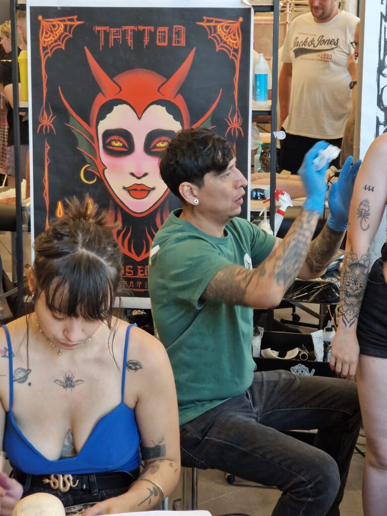 Tatoueur et participante devant des planches de flashs au Playground Tattoo Club